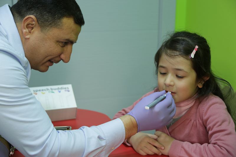 Therapist doing an oral-motor exercise with a girl